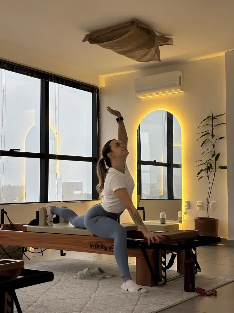 Estúdio da Cura Pilates: reformer de madeira diante da janela em arco